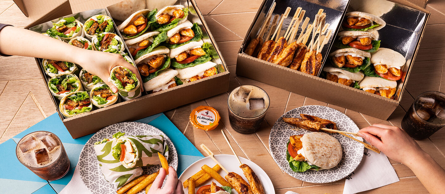 a Nando’s meal on a table including PERi-PERi chicken, a salad, chips, and a selection of sides